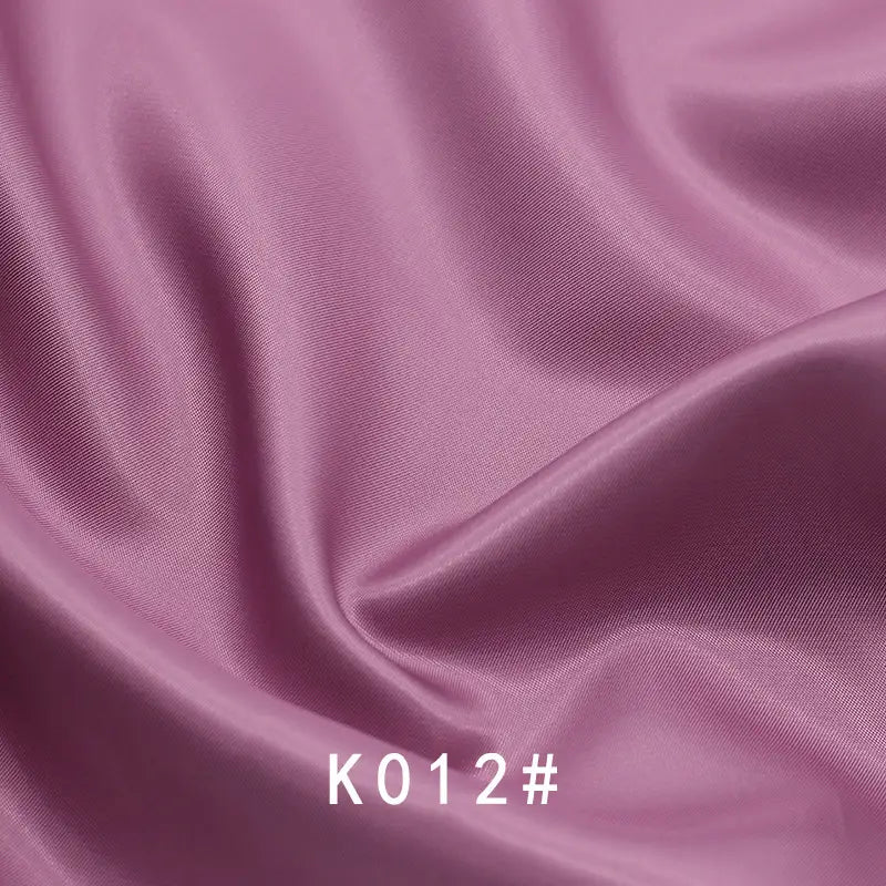 Smooth, shiny lavender-pink Colorful Satin Viscose Fabric By The Yard by Longan Craft with gentle folds and twill weave. "K012#" is displayed in white text at the bottom center. Perfect for elegant, formal dresses.