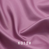 Smooth, shiny lavender-pink Colorful Satin Viscose Fabric By The Yard by Longan Craft with gentle folds and twill weave. "K012#" is displayed in white text at the bottom center. Perfect for elegant, formal dresses.