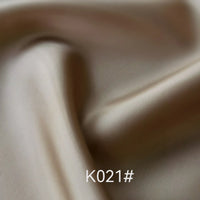 A close-up of smooth, light beige Colorful Satin Viscose Fabric By The Yard from Longan Craft shows gentle folds and a subtle sheen. The text "K021#" appears at the bottom center of the image.