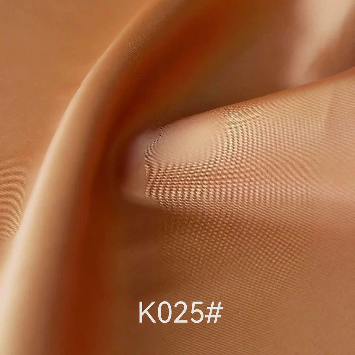 Close-up of smooth, shiny, light brown Colorful Satin Viscose Fabric By The Yard from Longan Craft with gentle folds and a soft texture. The text K025# is displayed at the bottom center of the image.