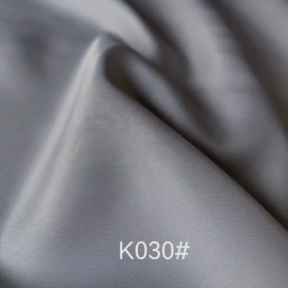 A close-up of colorful satin viscose fabric by the yard from Longan Craft shows its soft twill weave and smooth texture, ideal for formal dresses. The K030# code is displayed on the elegant polyester viscose material’s light grey surface.