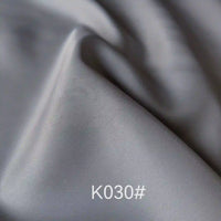 A close-up of colorful satin viscose fabric by the yard from Longan Craft shows its soft twill weave and smooth texture, ideal for formal dresses. The K030# code is displayed on the elegant polyester viscose material’s light grey surface.