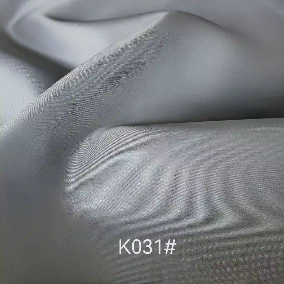 Close-up of smooth, light grey Colorful Satin Viscose Fabric By The Yard from Longan Craft with soft folds and subtle sheen, featuring twill weave—an elegant polyester viscose ideal for formal dresses. K031# shown as fabric code.