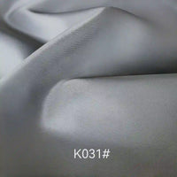 Close-up of smooth, light grey Colorful Satin Viscose Fabric By The Yard from Longan Craft with soft folds and subtle sheen, featuring twill weave—an elegant polyester viscose ideal for formal dresses. K031# shown as fabric code.
