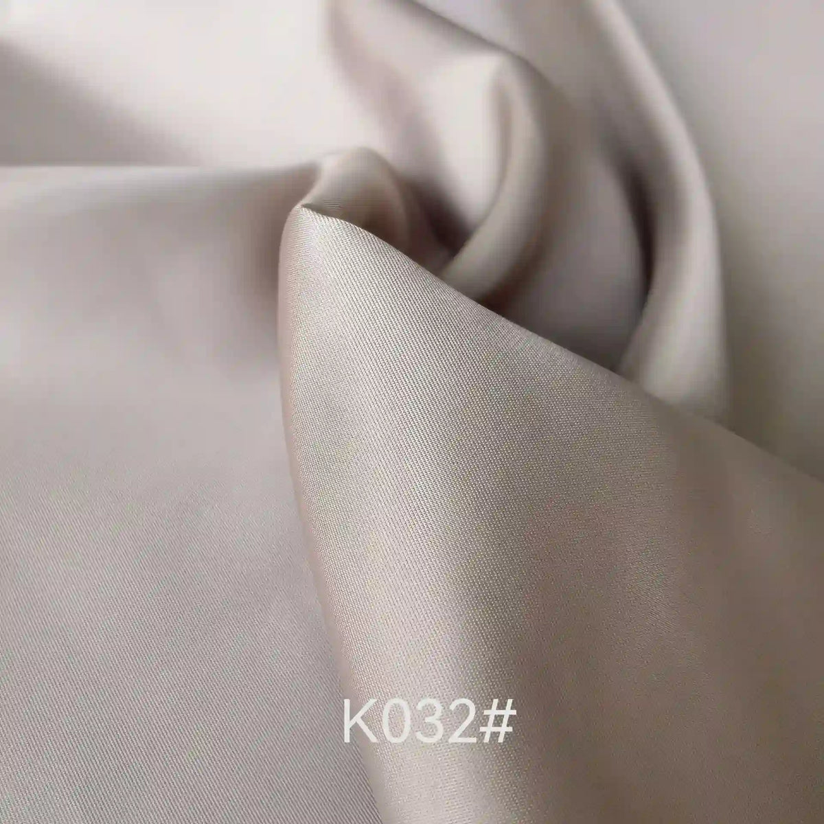 Close-up of smooth, light beige Colorful Satin Viscose Fabric By The Yard from Longan Craft, featuring a soft, shiny texture and gentle folds. The text K032# appears at the bottom center of the image.