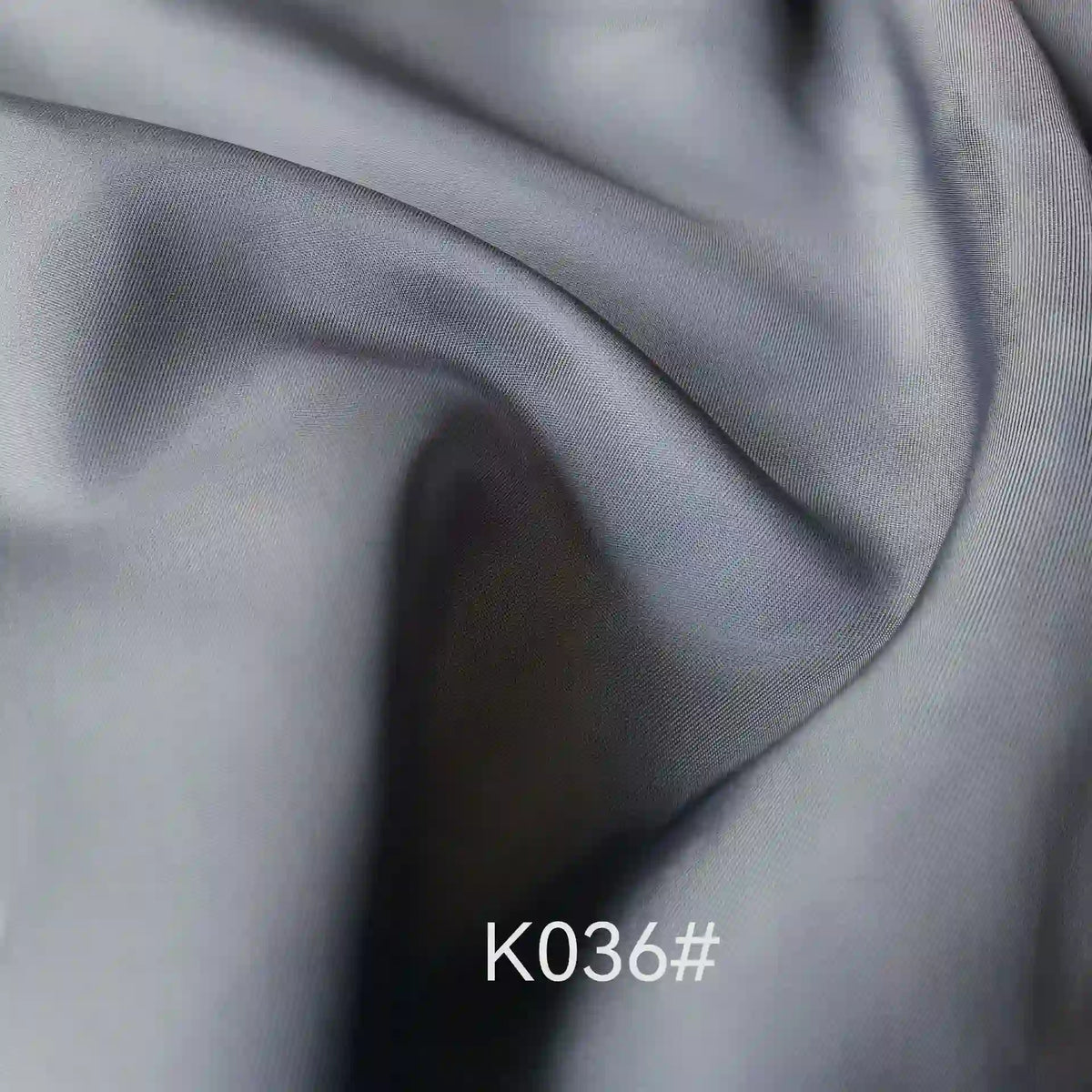 Elegant, light gray Colorful Satin Viscose Fabric by the yard from Longan Craft features a twill weave and soft, flowing folds—perfect for formal dresses. The text “K036#” is centered at the bottom of the image.