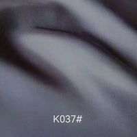 Close-up of smooth, folded gray Colorful Satin Viscose Fabric By The Yard by Longan Craft, showing twill weave with soft shadows and highlights. The code K037# is displayed at the bottom center of the image.