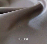 A close-up of smooth, folded grey Longan Craft Colorful Satin Viscose Fabric by the yard, featuring a soft texture and twill weave, code K038# shown at the bottom. Ideal for elegant formal dresses.