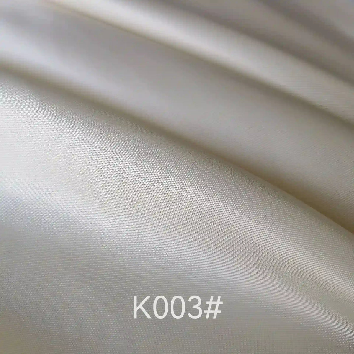 Close-up of smooth, shiny cream-colored Longan Craft Colorful Satin Viscose Fabric By The Yard with gentle folds and twill weave, ideal for formal dresses. "K003#" is displayed at the bottom center of the image.