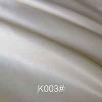 Close-up of smooth, shiny cream-colored Longan Craft Colorful Satin Viscose Fabric By The Yard with gentle folds and twill weave, ideal for formal dresses. "K003#" is displayed at the bottom center of the image.