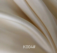 Close-up of smooth, light beige Colorful Satin Viscose Fabric By The Yard from Longan Craft, with gentle folds and a soft sheen. The text K004# is overlaid at the bottom center of the image.