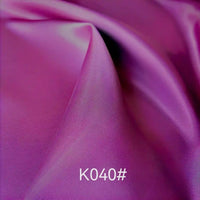 A close-up of Longan Craft's Colorful Satin Viscose Fabric By The Yard in purple, showing its smooth, shiny twill weave and soft folds; the code K040# appears in white text at the bottom center of the image.
