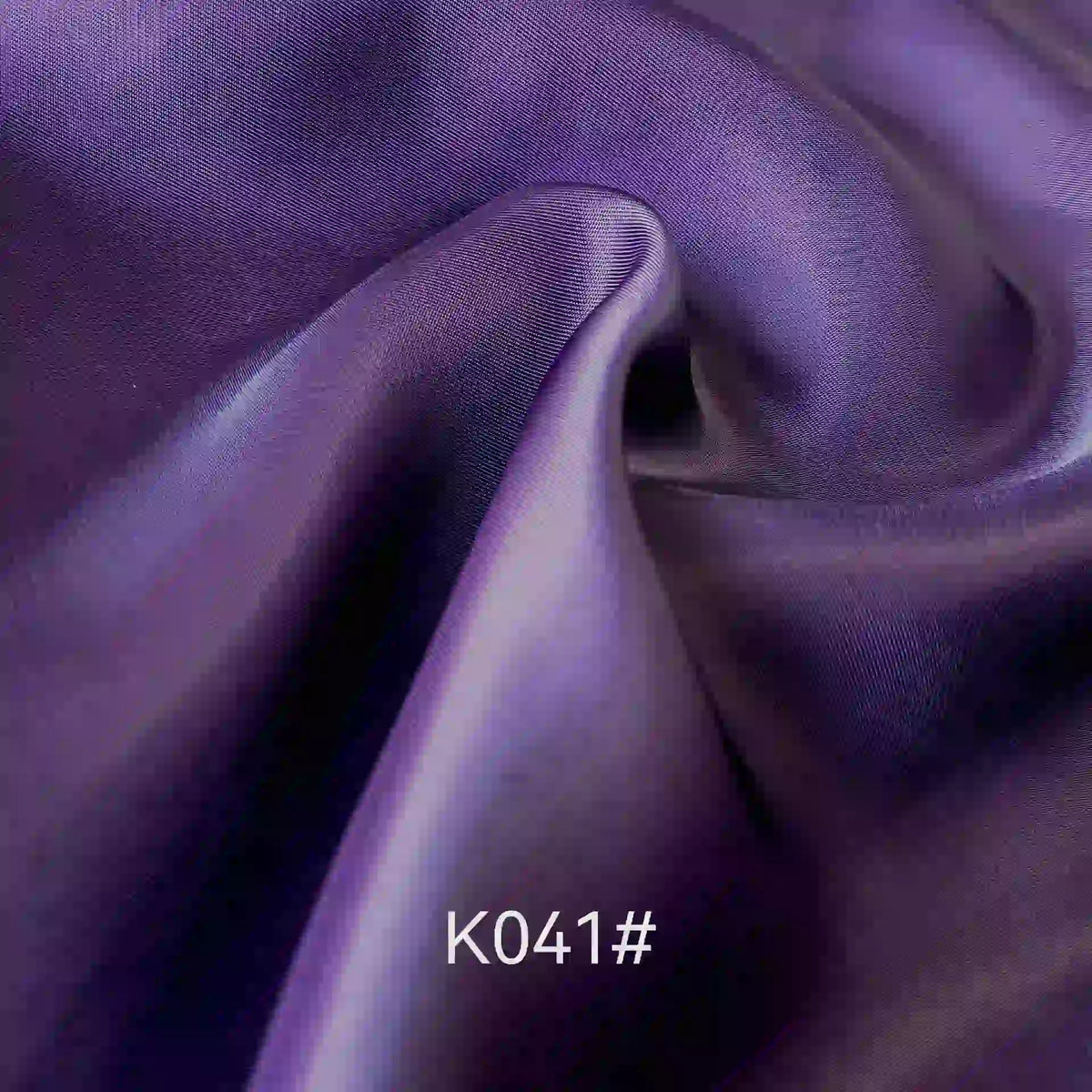 A close-up of smooth, flowing purple Colorful Satin Viscose Fabric by Longan Craft with twill weave, soft folds, and highlights. The text K041# is displayed at the bottom center of the image.
