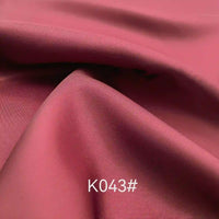 A close-up of smooth, rose pink Colorful Satin Viscose Fabric by Longan Craft, with gentle folds and twill weave. "K043#" is written in white at the bottom center, showcasing this elegant material ideal for formal dresses.