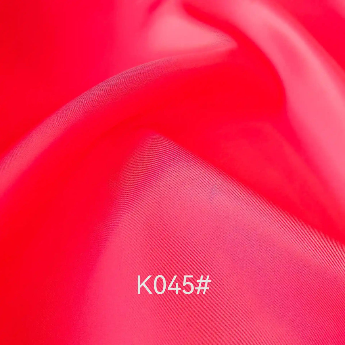 Close-up of smooth, vibrant pink satin viscose fabric from Longan Craft, featuring a twill weave and soft folds. "K045#" appears in white at the bottom center. Ideal for formal dresses, this elegant material is sold by the yard.