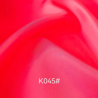 Close-up of smooth, vibrant pink satin viscose fabric from Longan Craft, featuring a twill weave and soft folds. "K045#" appears in white at the bottom center. Ideal for formal dresses, this elegant material is sold by the yard.