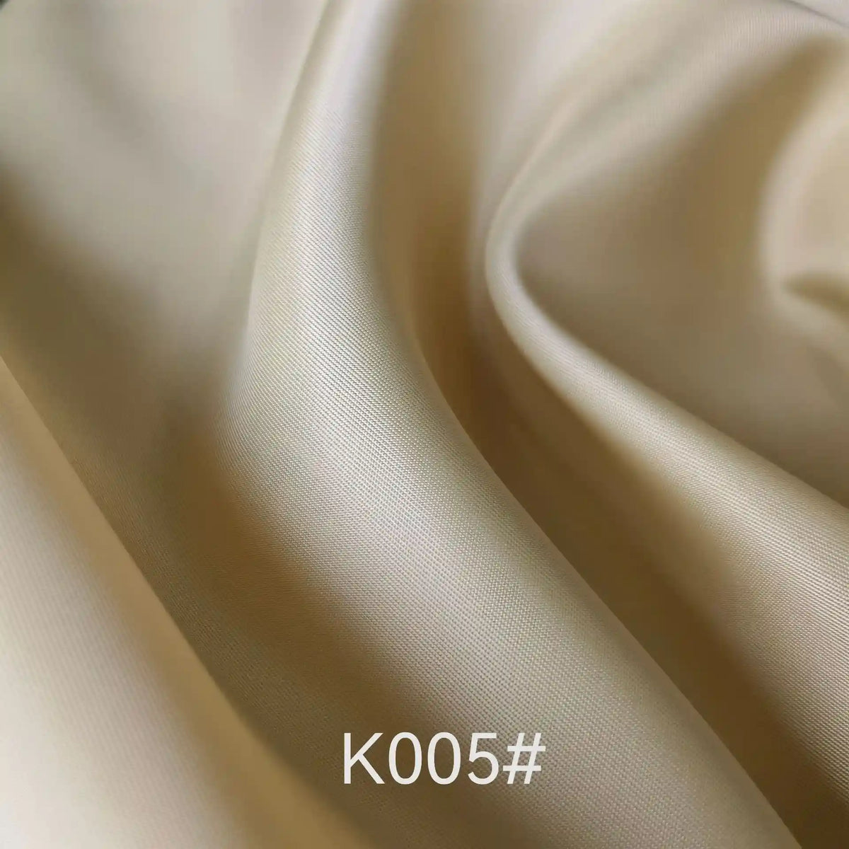 Close-up of smooth, light beige Longan Craft Colorful Satin Viscose Fabric By The Yard with gentle folds and soft texture. Polyester viscose twill weave, perfect for formal dresses. Product code K005# visible at the bottom.