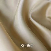 Close-up of smooth, light beige Longan Craft Colorful Satin Viscose Fabric By The Yard with gentle folds and soft texture. Polyester viscose twill weave, perfect for formal dresses. Product code K005# visible at the bottom.