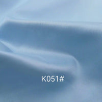 Light blue Colorful Satin Viscose Fabric By The Yard from Longan Craft, featuring a soft texture and gentle folds. Twill weave polyester viscose material ideal for formal dresses. Code K051# appears in white at the center of the image.