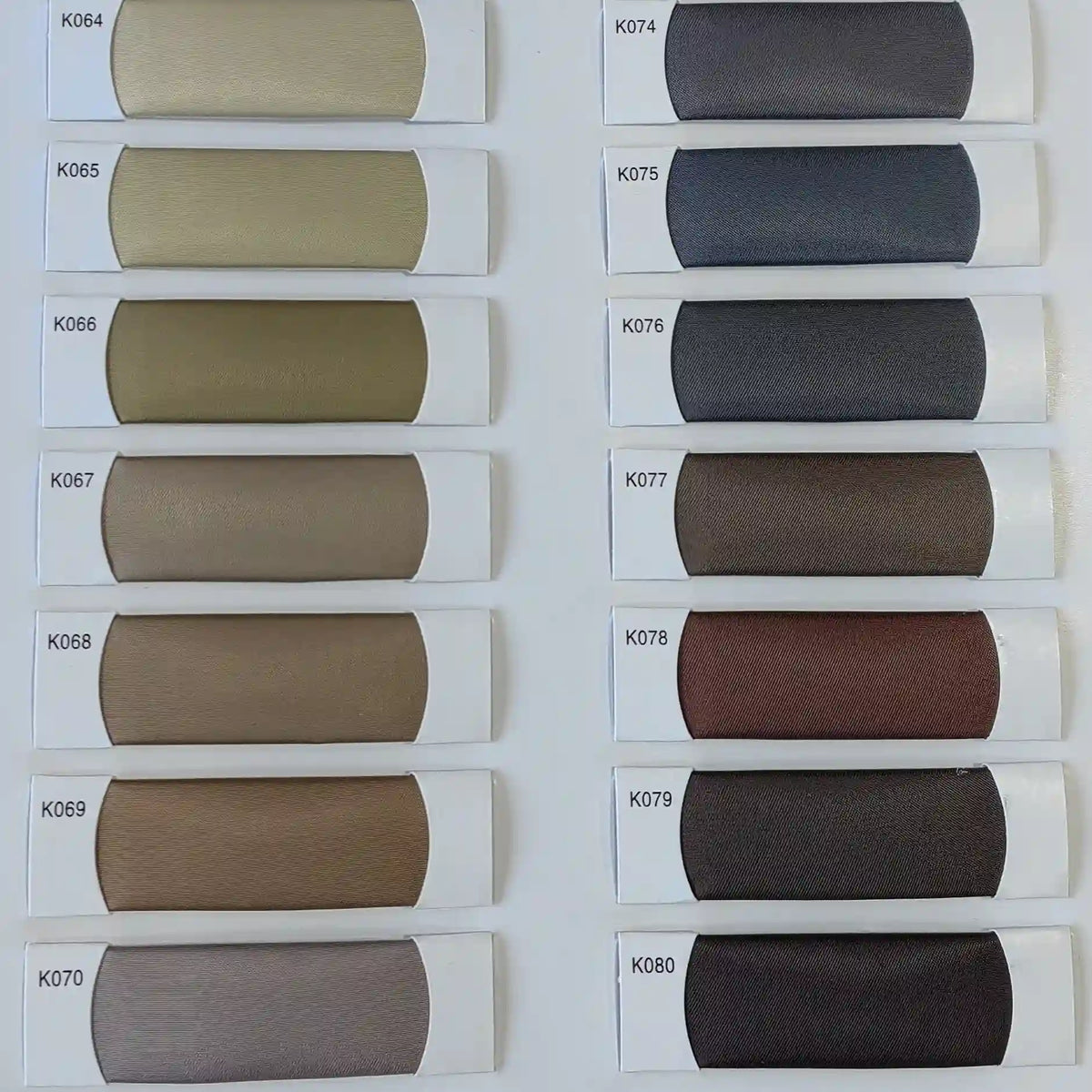 Twelve Colorful Satin Viscose Fabric swatches by Longan Craft (K064–K080) are arranged in two columns on a white background, showcasing elegant beige, brown, gray, and blue shades—ideal for formal dresses and crafts.