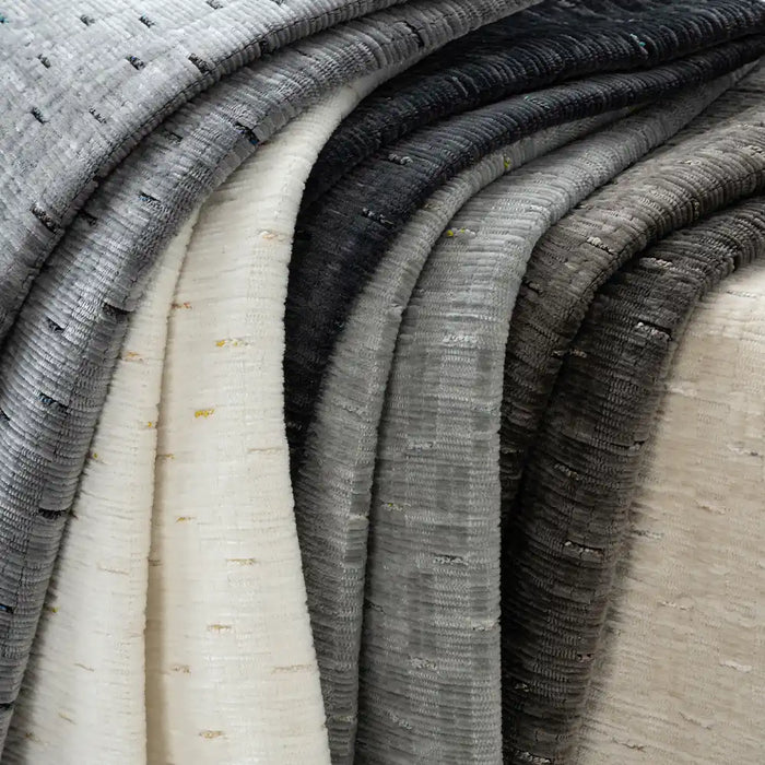 Several rolls of Longan Craft's Colorful Slub Chenille Fabric By The Yard, a slubby textured heavyweight chenille, are displayed in white, gray, and black gradients—perfect soft material for modern home decor and upholstery.