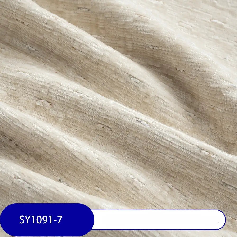 Close-up of Longan Craft's Colorful Slub Chenille Fabric By The Yard—heavyweight, cream-colored with a subtle woven pattern. Soft folds highlight its slubby texture. A blue label at bottom left shows code SY1091-7.