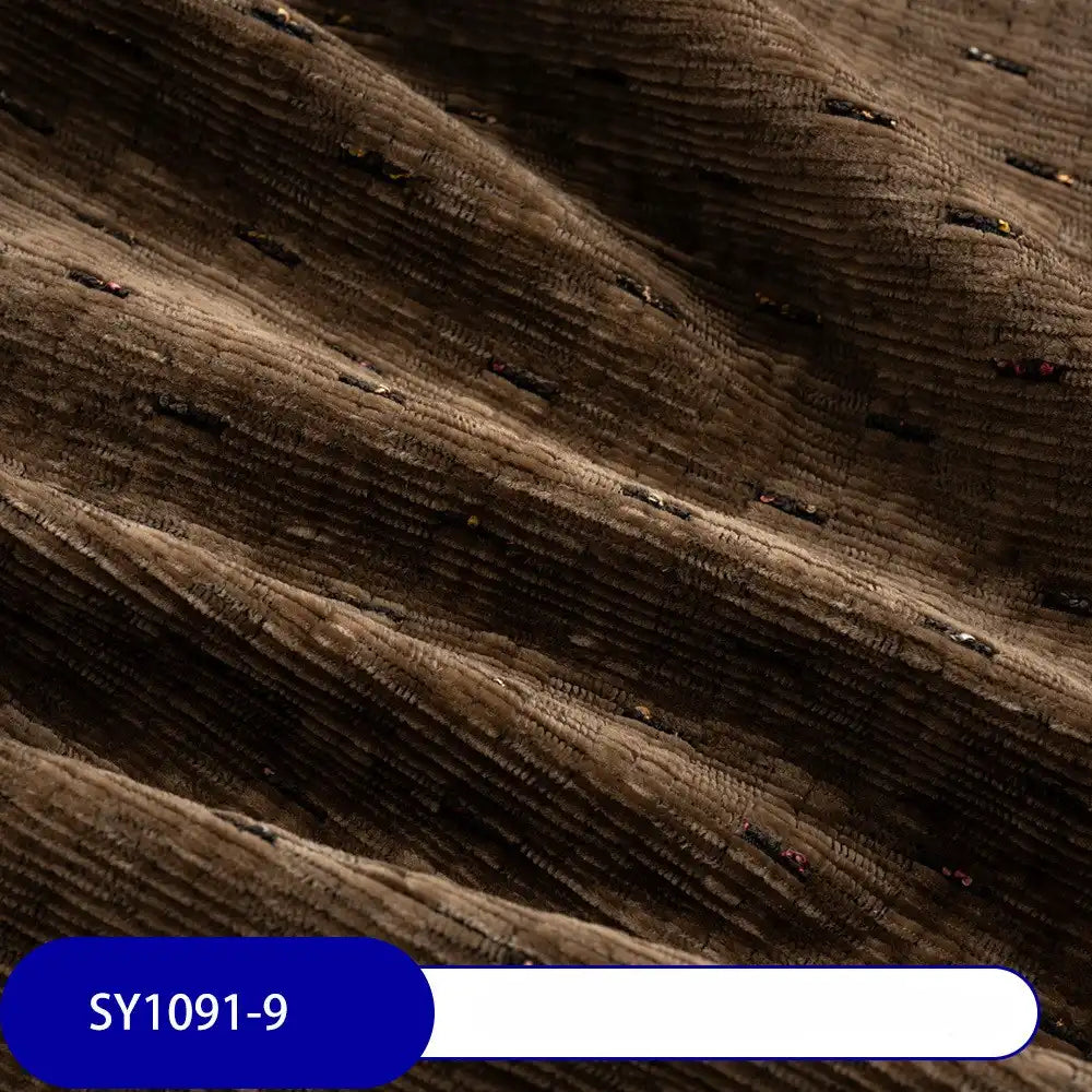 Close-up of Longan Craft’s Colorful Slub Chenille Fabric By The Yard, a heavyweight, slubby-textured chenille material in rich brown with vibrant flecks. Featured is the soft upholstery fabric gently folded, label SY1091-9 visible at the bottom.