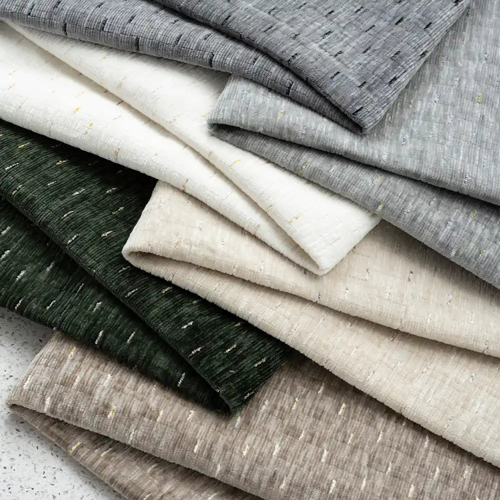 A stack of Longan Craft Colorful Slub Chenille Fabric By The Yard, featuring slubby textured heavyweight polyester chenille in neutral shades, is arranged on a speckled surface. Ideal for home decor projects.
