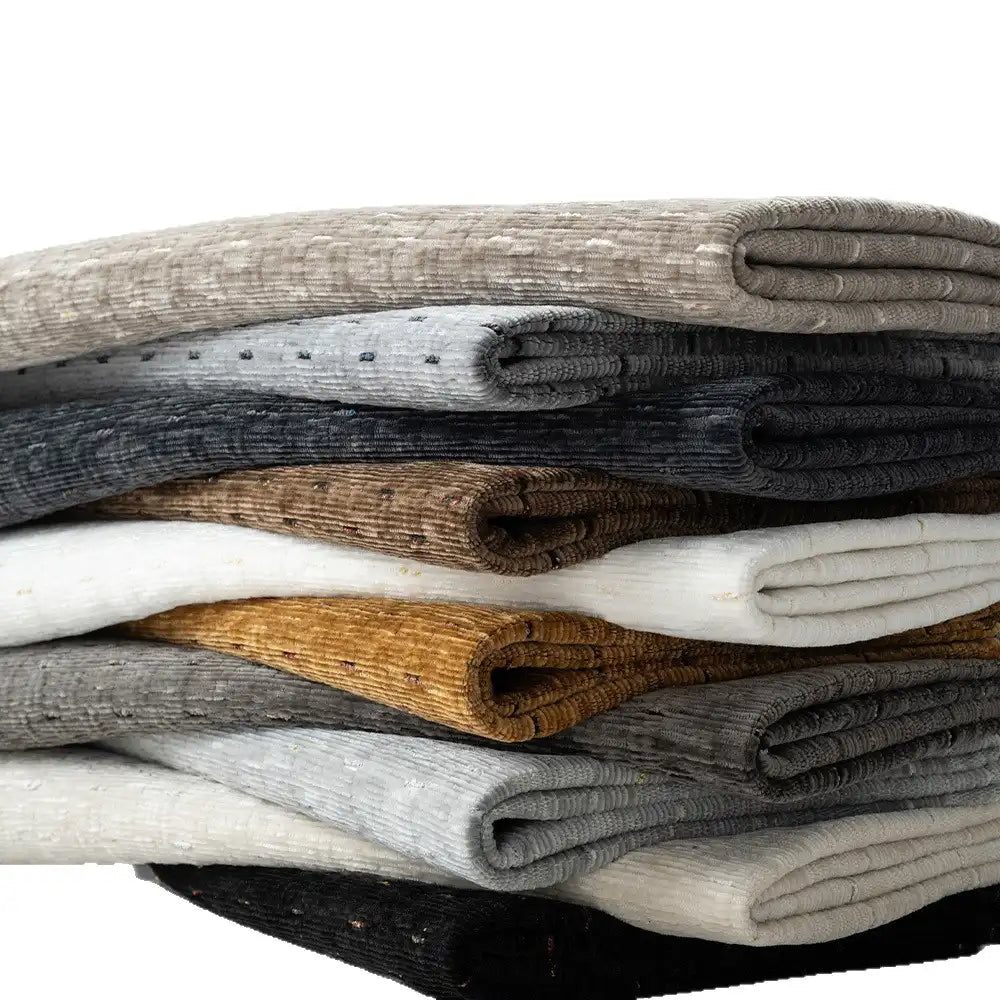 A stack of Longan Craft’s Colorful Slub Chenille Fabric by the yard—soft, slubby textured heavyweight chenille in gray, black, white, brown, and beige—is neatly arranged against a white background.