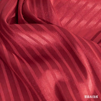 A close-up of Longan Craft’s Colorful Striped Jacquard Satin Fabric shows alternating shiny and matte stripes on smooth, breathable polyester—ideal for dressmaking. The soft satin texture is highlighted by subtle wrinkles.