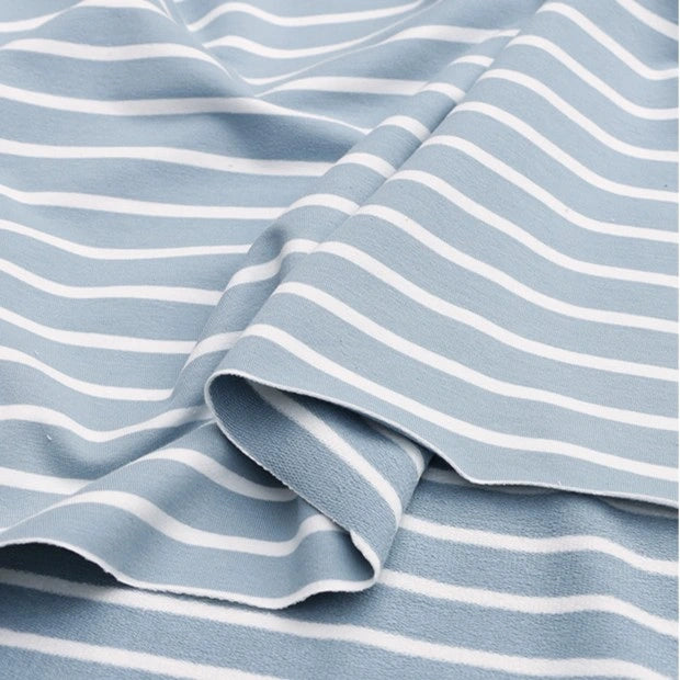 A close-up of Longan Craft’s Colorful Striped Stretch French Terry Fabric shows light blue cotton-spandex knit with evenly spaced white stripes, gently folded to create soft waves—ideal for sweatshirts by the yard.