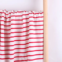 The Colorful Striped Stretch French Terry Fabric by Longan Craft is displayed draped on a wooden rod against a light background, highlighting its vibrant red stripes—perfect knit cotton material for sweatshirts.