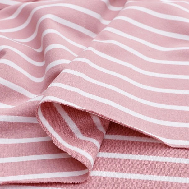 A close-up of Longan Craft’s Colorful Striped Stretch French Terry fabric shows soft pink cotton-spandex knit with horizontal white stripes, perfect for sweatshirts and activewear. Fabric is gently folded, creating subtle curves and shadows.