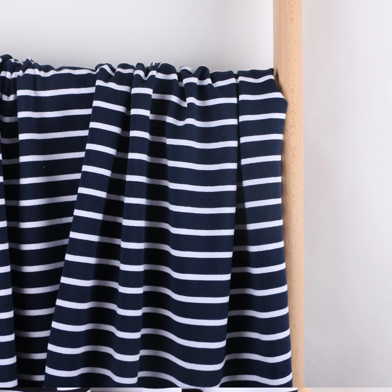 Longan Craft's Colorful Striped Stretch French Terry Fabric by the yard—a knit cotton French terry perfect for sweatshirts—is draped over a light wooden rod against a plain white background.