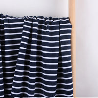 Longan Craft's Colorful Striped Stretch French Terry Fabric by the yard—a knit cotton French terry perfect for sweatshirts—is draped over a light wooden rod against a plain white background.