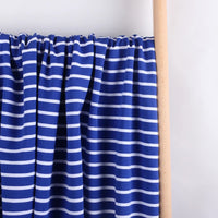 Colorful Striped Stretch French Terry Fabric by Longan Craft, a soft cotton-spandex knit perfect for sweatshirts, is displayed hanging from a light wooden rod against a plain white background.