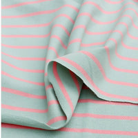 A close-up of Longan Craft's Colorful Striped Stretch French Terry Fabric By The Yard, a knit cotton material in light blue with evenly spaced pink stripes, featuring a slightly folded and textured surface—ideal for sweatshirts.