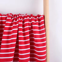 A piece of Longan Craft Colorful Striped Stretch French Terry Fabric By The Yard, featuring evenly spaced white stripes on red, is draped over a light wooden rod against a plain white background. Perfect for sweatshirts.