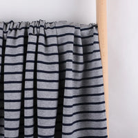A piece of Longan Craft Colorful Striped Stretch French Terry Fabric, a knit cotton French terry perfect for sweatshirts, is draped over a light wooden rod against a plain white background.
