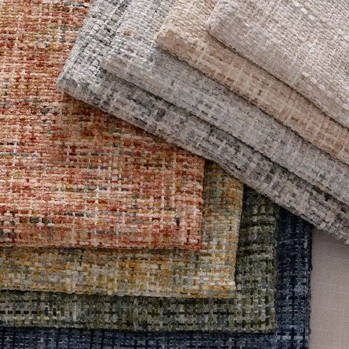 A vibrant stack of Longan Craft's Colorful Tweed Chenille Fabric By The Yard showcases textured woven chenille in beige, gray, orange, green, and blue—a soft upholstery fabric perfect for clothing.