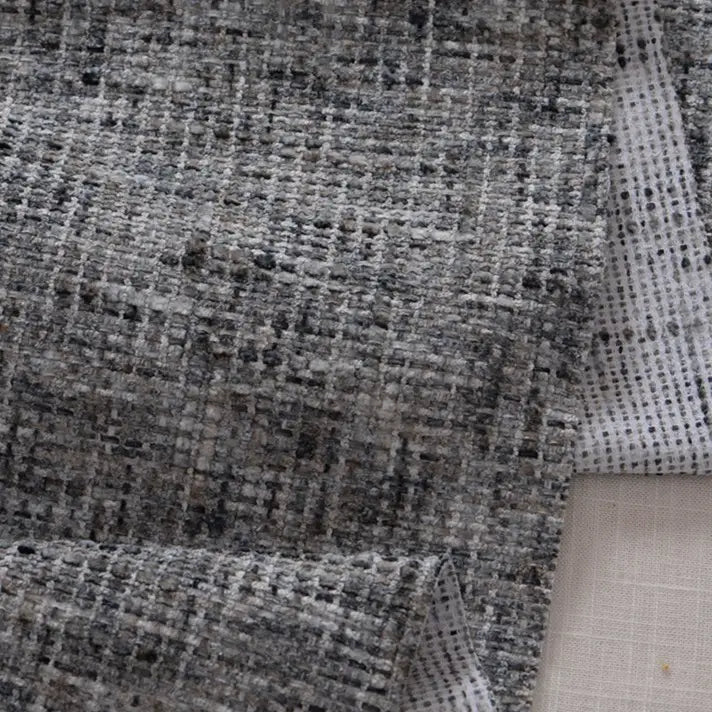 Close-up of Longan Craft's Colorful Tweed Chenille Fabric by the yard, showing its textured grey and black weave with a white grid-patterned backing. This soft chenille fabric is perfect for adding depth to clothing and design projects.
