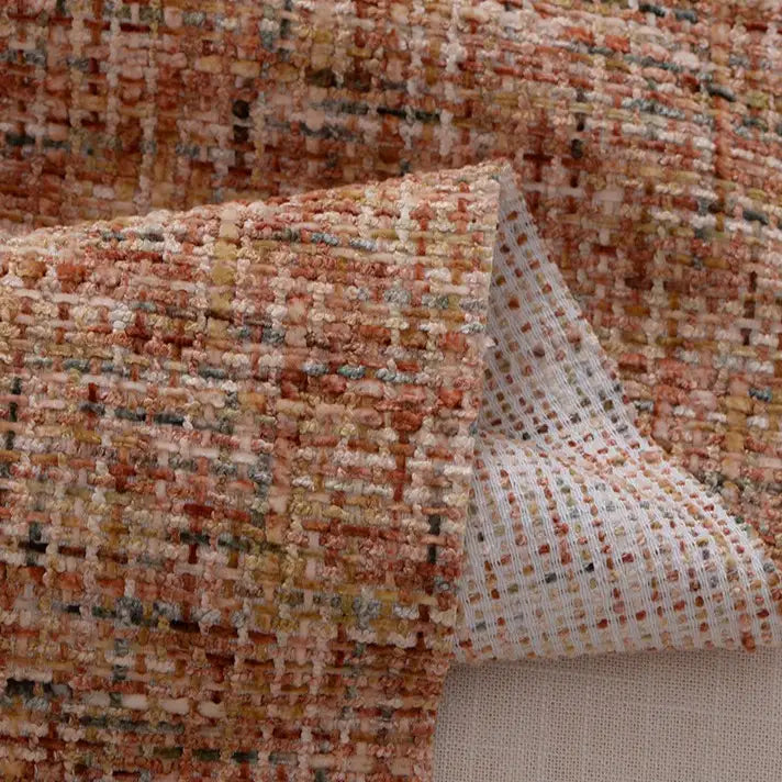 A close-up of Longan Craft’s Colorful Tweed Chenille Fabric By The Yard shows its textured, woven orange, beige, brown, and gold design, with a white grid reverse—ideal soft chenille fabric for clothing and upholstery.