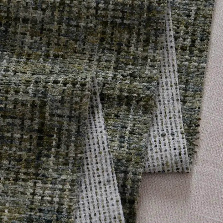 A close-up of Longan Craft's Colorful Tweed Chenille Fabric By The Yard shows its grid-like woven pattern in green, gray, and black shades, draped softly. This textured chenille is ideal for clothing and upholstery.