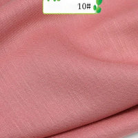 A close-up of Colorful Twill 100 Lyocell Fabric by Longan Craft shows its pink, slightly ribbed texture, with a partial label displaying green text and the number 10#. This sustainable material is ideal for comfortable suits.