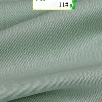 A close-up of light green Colorful Twill 100 Lyocell Fabric by Longan Craft shows smooth, slightly shiny, diagonally textured sustainable material with gentle folds. A partial label with green accents and "11#" appears at the top.