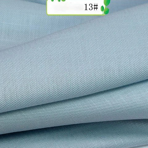 Close-up of light blue Colorful Twill 100 Lyocell Fabric by Longan Craft, showing a soft, smooth texture and fine diagonal weave. A small label marked 13# is partially visible at the top. Sustainable lyocell material for suits.