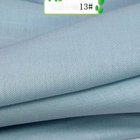 Close-up of light blue Colorful Twill 100 Lyocell Fabric by Longan Craft, showing a soft, smooth texture and fine diagonal weave. A small label marked 13# is partially visible at the top. Sustainable lyocell material for suits.