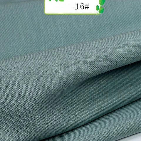 Close-up of folded Colorful Twill 100 Lyocell Fabric by Longan Craft in light teal, showing its subtle texture. A label marked 16# with green leaf graphics highlights this sustainable and comfortable suit material.