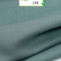 Close-up of folded Colorful Twill 100 Lyocell Fabric by Longan Craft in light teal, showing its subtle texture. A label marked 16# with green leaf graphics highlights this sustainable and comfortable suit material.