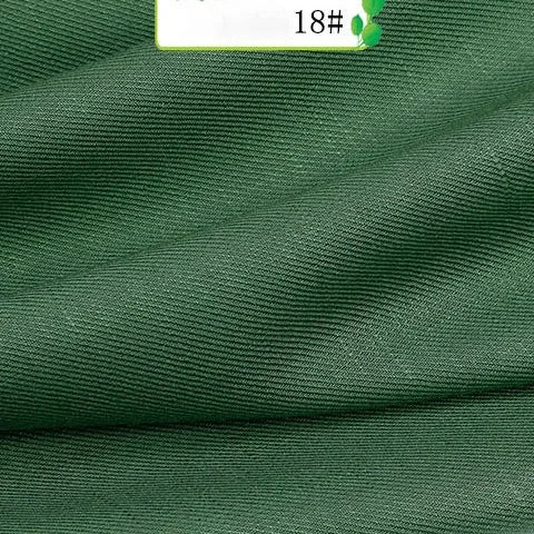 Close-up of Colorful Twill 100 Lyocell Fabric By The Yard from Longan Craft, showing green ribbed texture and soft folds; a white label with "18#" and two green leaf graphics highlights this sustainable material for suits.